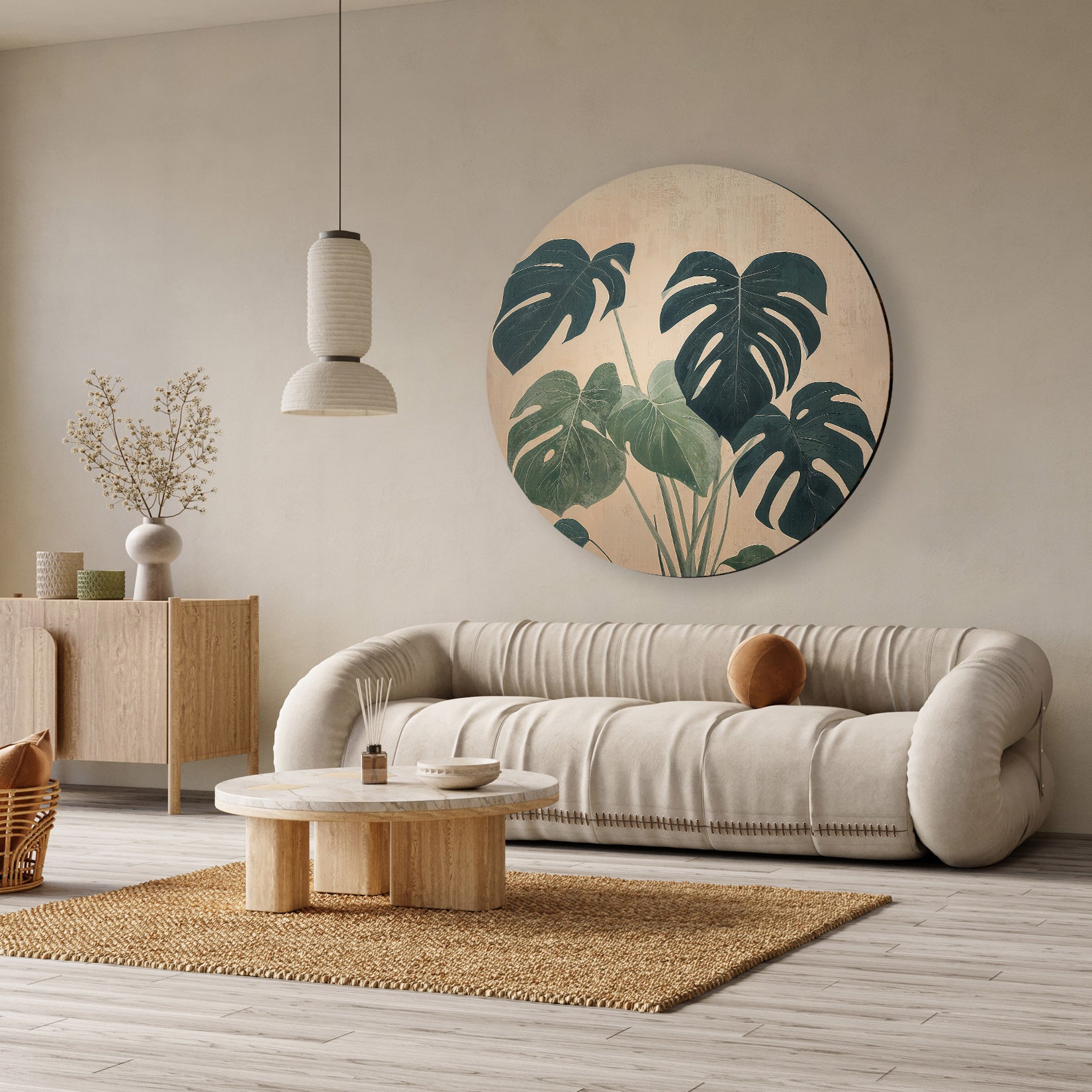 Aluminium muurcirkel Monstera boven een beige bank in een lichte woonkamer.