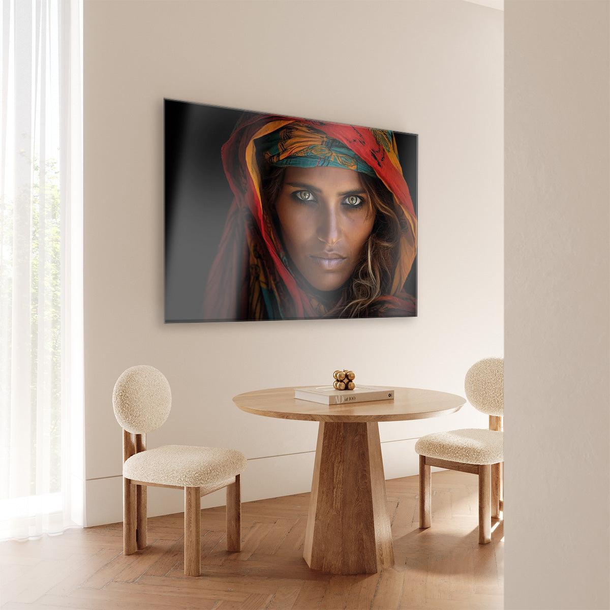 Plexiglas schilderij Vrouw 5 aan de muur bij een ronde houten eettafel.